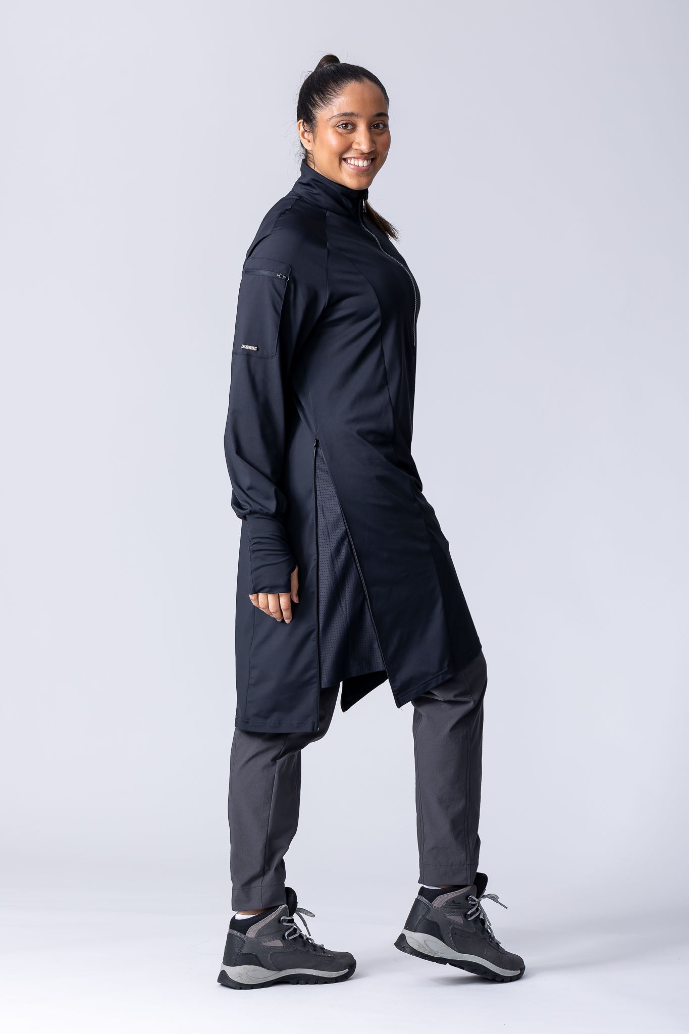 Long line tunic top in black. With front zipper, hidden side panels, back breathability panel and waist belt with buckle.