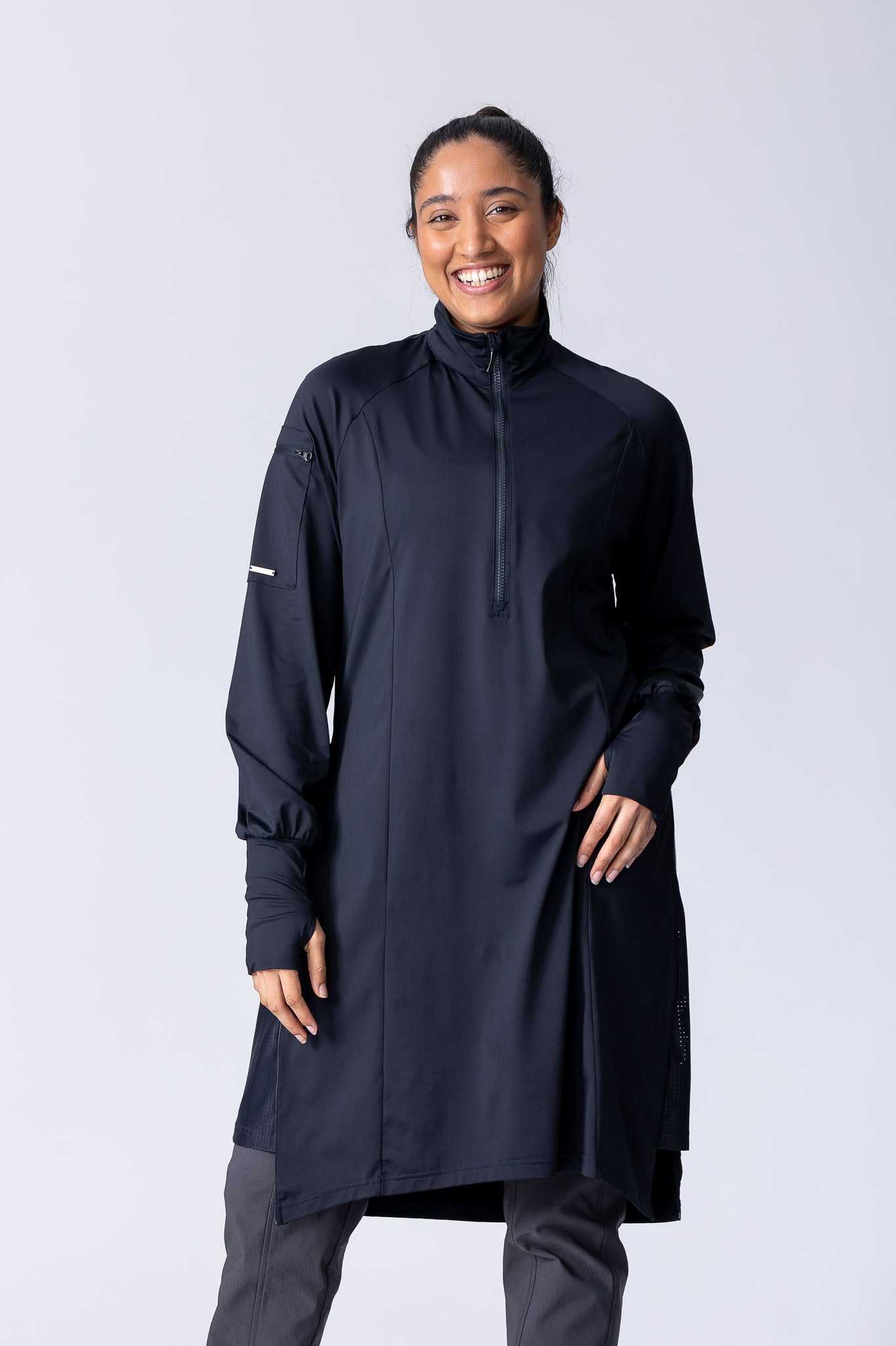 Long line tunic top in black. With front zipper, hidden side panels, back breathability panel and waist belt with buckle.