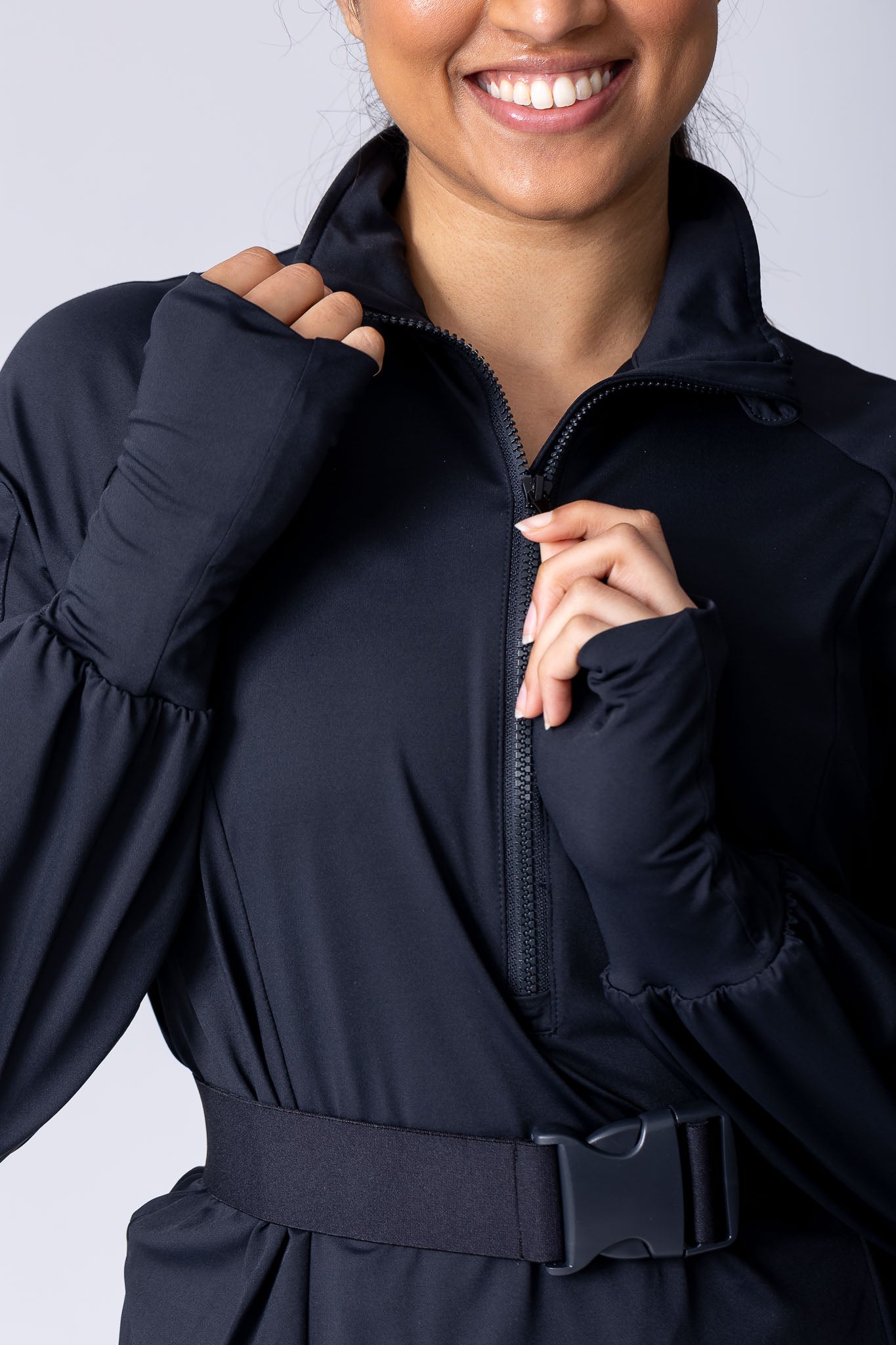 Long line tunic top in black. With front zipper, hidden side panels, back breathability panel and waist belt with buckle.