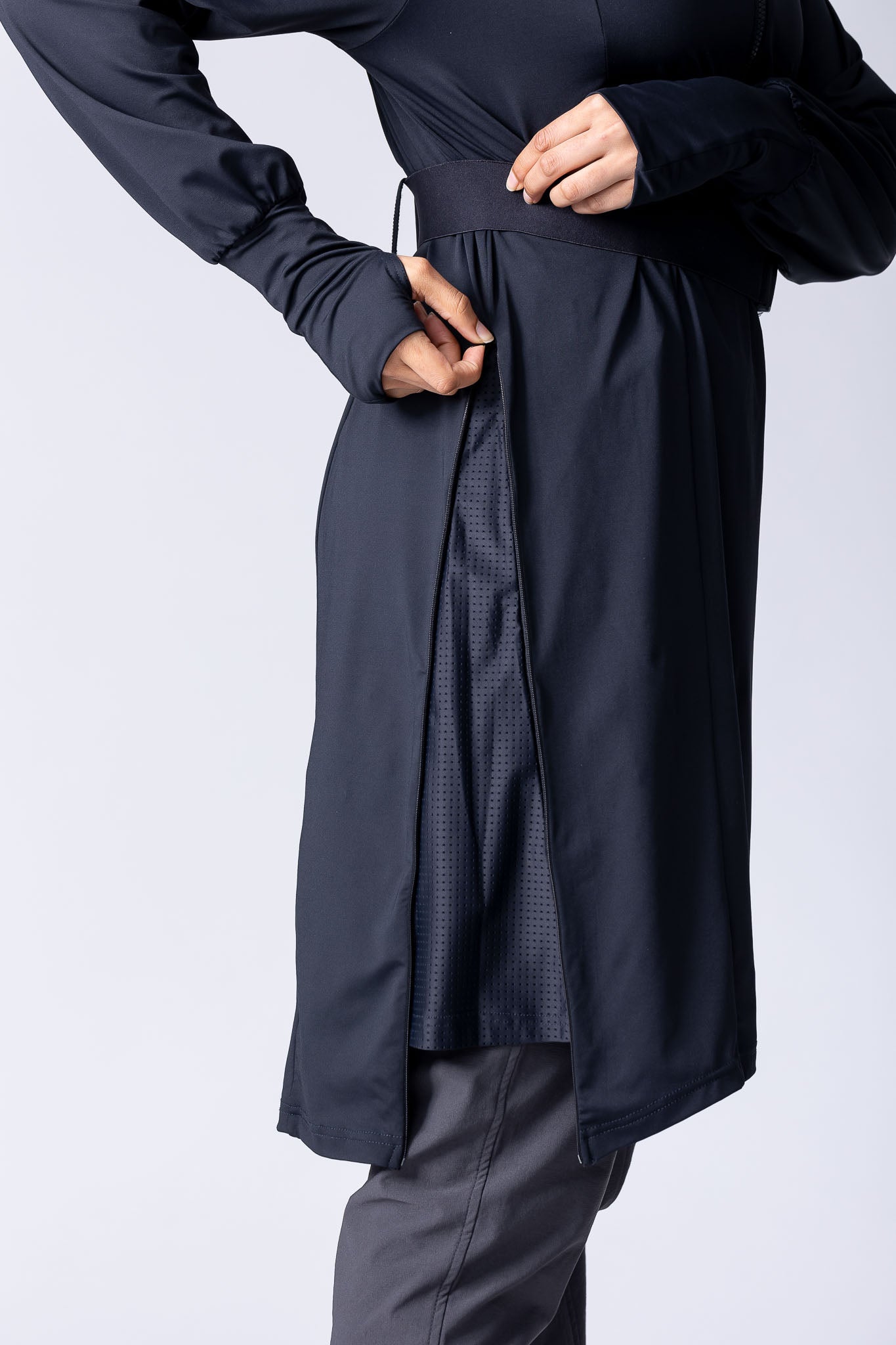 Long line tunic top in black. With front zipper, hidden side panels, back breathability panel and waist belt with buckle.
