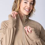 Long line tunic top in beige. With front zipper, hidden side panels, back breathability panel and waist belt with buckle.