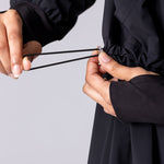 Light weight long line hoodie in black with adjustable waist, front pocket and large hood.