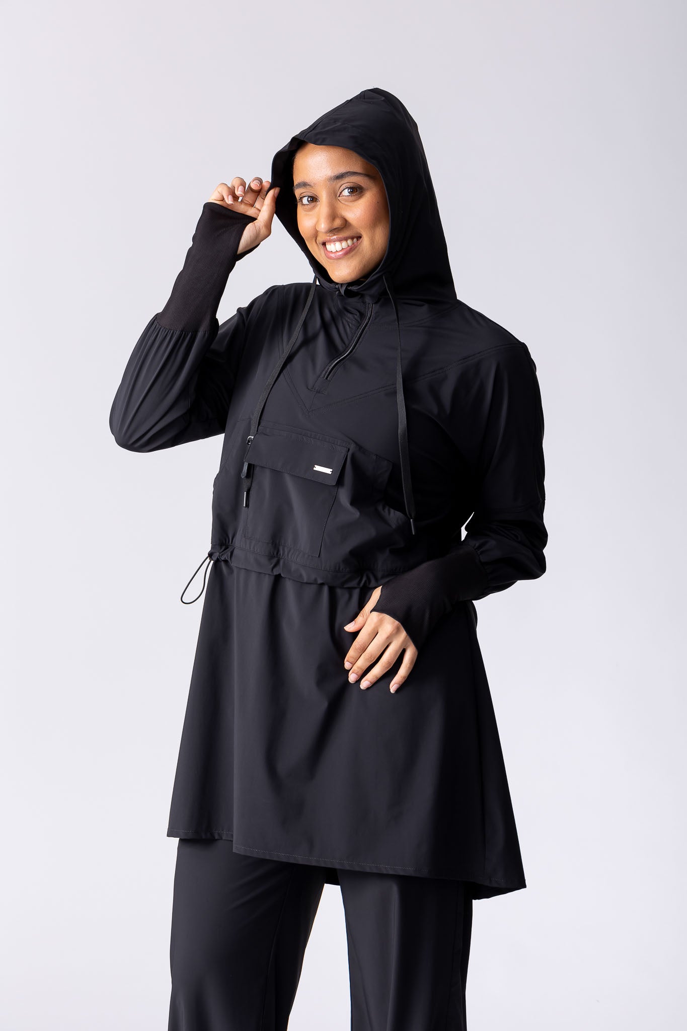 Light weight long line hoodie in black with adjustable waist, front pocket and large hood.