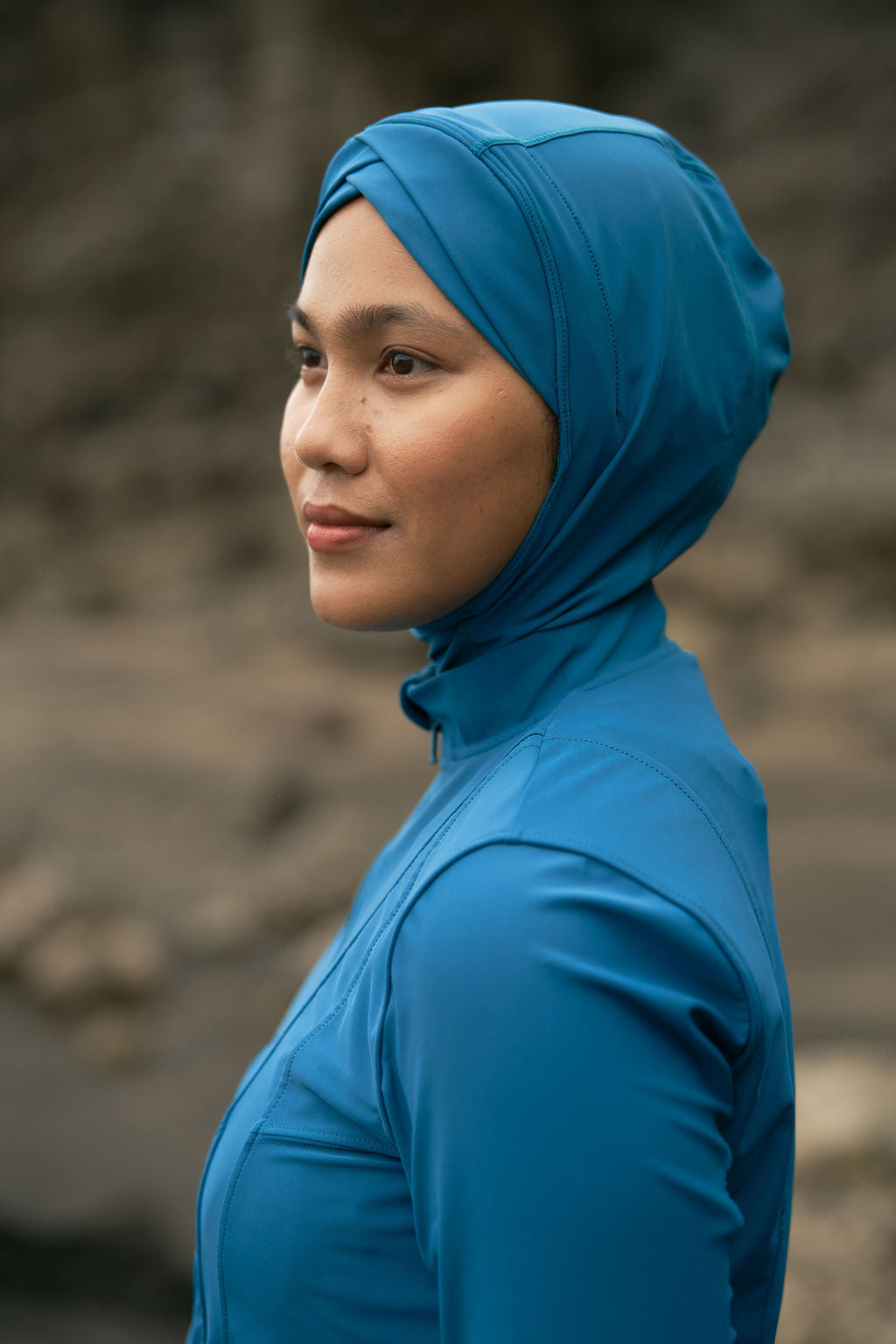 Woman wearing a blue hijab and shirt against a natural background