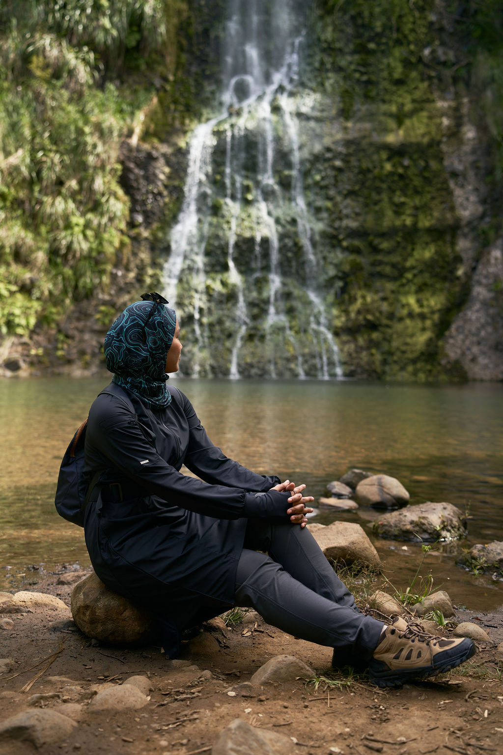 Person sitting by a waterfall in a natural setting