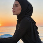 Woman in a hijab on a paddleboard at sunset