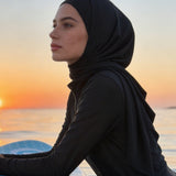 Woman in a hijab on a paddleboard at sunset