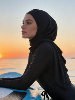 Woman in a hijab on a paddleboard at sunset