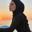 Woman in a hijab on a paddleboard at sunset