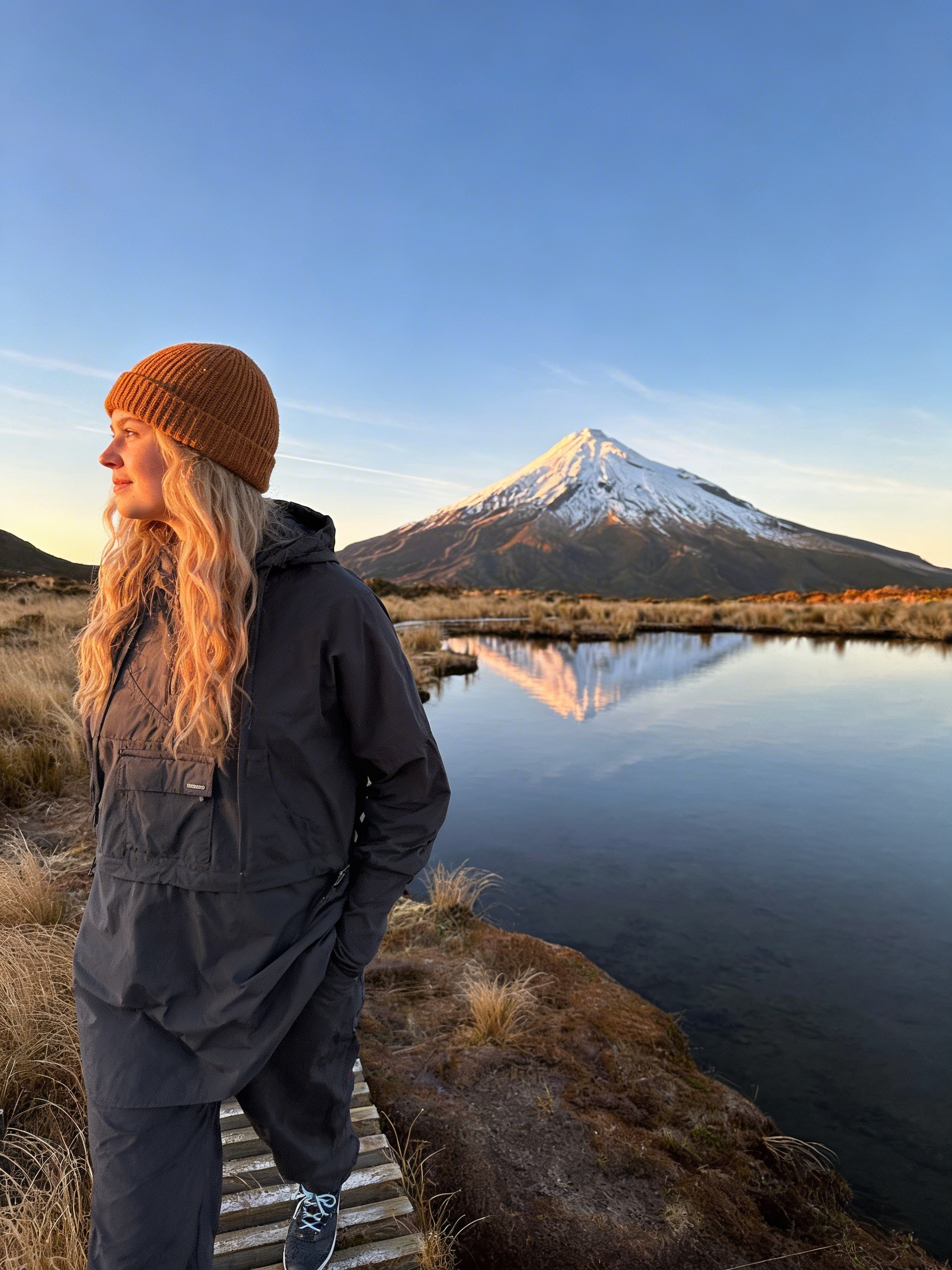 Person standing by a lake with a mountain in the background